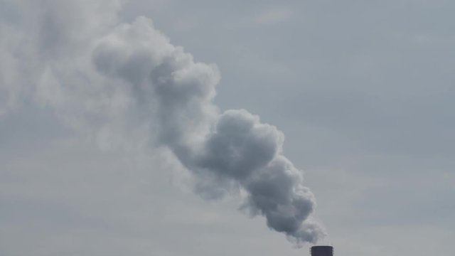 Factory plant smoke stack over blue sky background. Energy generation and air environment pollution industrial scene. Slow motion.