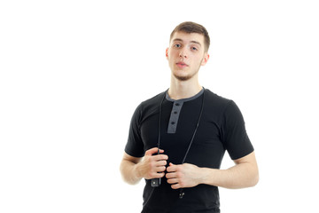 charming young guy in the black shirt looks straight and keeps the neck headphones