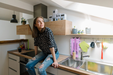 Young woman sitting in her new kitchen and looking out the window