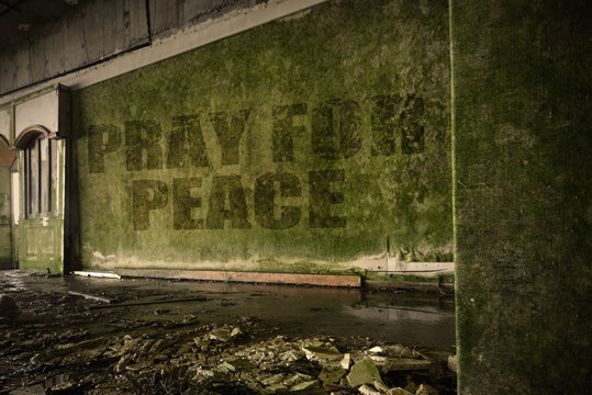 text pray for peace on the dirty wall in an abandoned ruined house