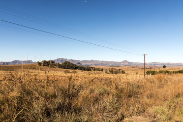 Winter Grassland with Overhead Power Lines Against Mountain Range