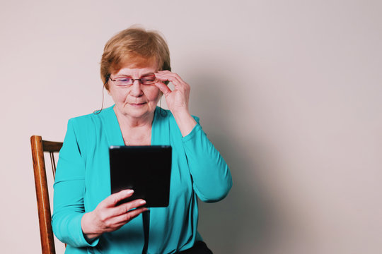 Thoughtful old woman searching on tablet
