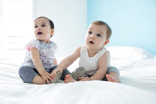 Two cute baby girls relaxing on bed