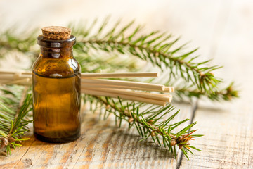 fir branches and spruce aroma oil on wooden table background