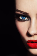 Close-up shot of woman's face with red lips and smoky eyes, selective focus