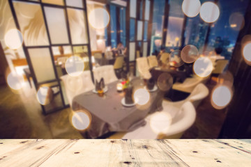 image of wooden table in front of abstract blurred background of restaurant lights