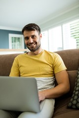 Portrait of man using laptop in living room