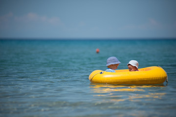 Brother and sister sitting in inflatable boat in the sea