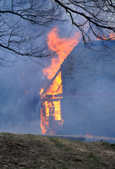 Fototapeta na wymiar Burning wooden house. Burning fire flame on wooden house roof. Building covered by flame.