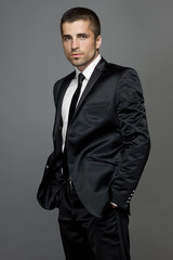 A man with a light unshaven in a stylish black suit