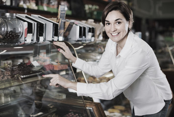 Female customer examining desserts in confectionery