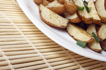 Baked potatoes with green onions on a white plate. Organic Vegetarian Food on a bamboo mat