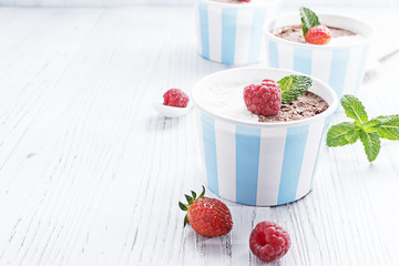 Chocolate vanilla ice cream with summer berries on white wooden board. Selective focus, copy space.