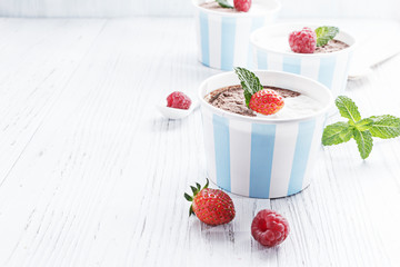 Chocolate vanilla ice cream with summer berries on white wooden board. Selective focus, copy space.
