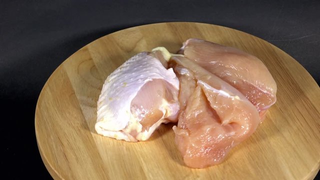 Raw chicken breast fillets is rotating on wooden background