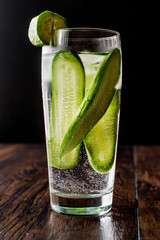 Cucumber Cocktail with vodka and tonic on dark wooden surface.