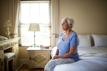 Worried senior woman sitting on bed in the bedroom - Powered by Adobe