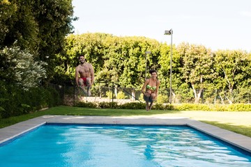 Young couple jumping together in the pool