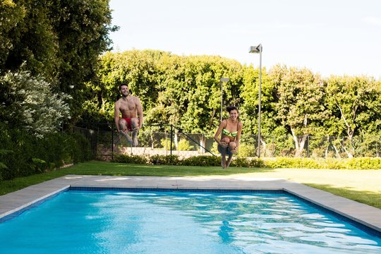 Young couple jumping together in the pool