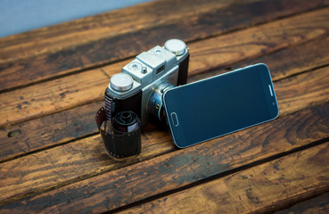 Vintage camera next to a cell phone