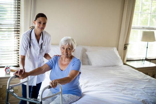 Female doctor helping senior woman to walk with a walker