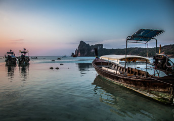 KO PHI PHI, THAILAND, January 31, 2014: Traditional long tail boats on the beach at sunset, Ko Phi Phi, Andaman Sea, famous tourist destination in Thailand
