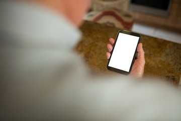 Obraz premium Senior man holding mobile phone in the ktchen