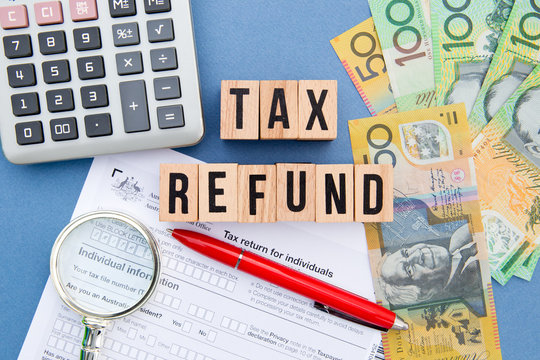 Tax Refund - Australia - wooden letters with tax form, magnifying glass, money and calculator
