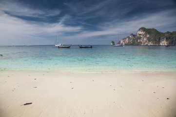 Obraz premium KO PHI PHI, THAILAND, February 1, 2014: Tropical beach with traditional long tail boats on the beach of Ko Phi Phi, Andaman Sea, famous tourist destination in Thailand