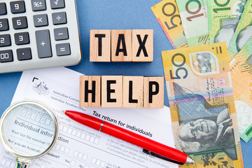 Tax Help - Australia - wooden letters with tax form, magnifying glass, money and calculator
