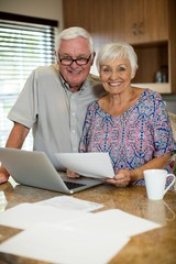 Senior couple calculating their invoices with laptop 