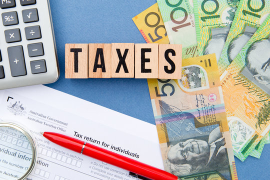 Taxes - Australia - wooden letters with tax form, magnifying glass, money and calculator
