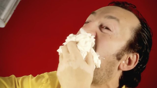 A funny ugly man spraying whipped cream directly into his mouth, feeling hungry, being glutton and proud. Close-up shot.
