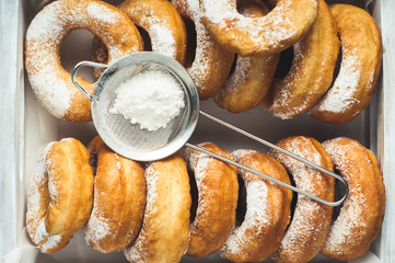 Homemade donuts with powdered sugar in a white wooden box