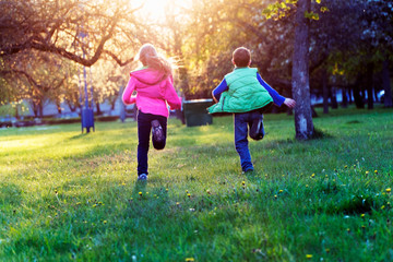 Children are running to the sunset on the grass in the park