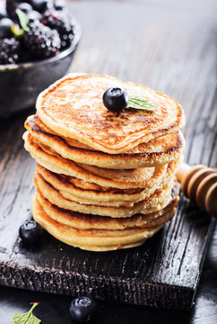 Stack of pancakes with fresh berries served on old black board . Selective focus.