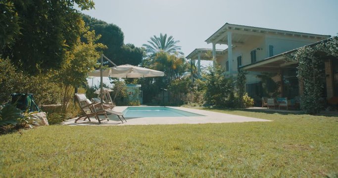 Tracking shot of a large backyard with a swimming pool in a luxury house