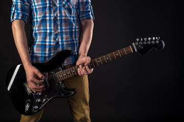 Music and art. The guitarist holds an electric guitar in his hands, on a black isolated background. Playing guitar. Horizontal frame