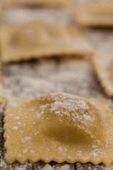 Ravioli pasta dusted with floor on wooden background
