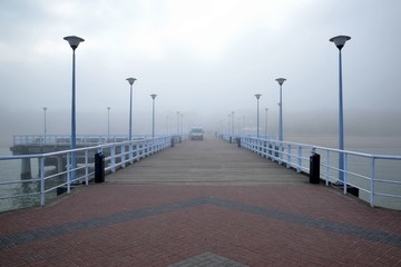Pier overlooking the misty beach by the sea