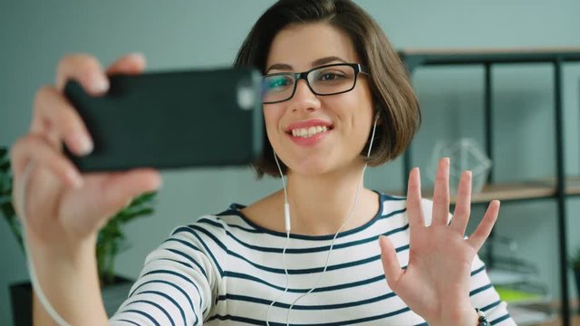 Attractive woman talking to a friend on video call on smart phone. Video chatting in ht office
