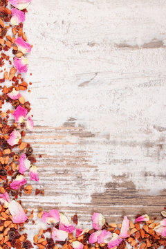 Frame of dried wild rose petals and tea grains, copy space for text on old rustic board