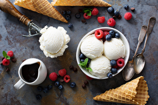 Vanilla ice cream scoops in a bowl with fresh berries
