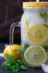 Lemonade. Sassy water. Refreshing cold drink with mint, cucumber, lemons. Sliced lemons with mint in mason jar  filled with ice and water. Mojito. Every day drink.
