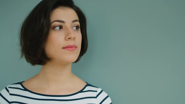 Portrait of young attractive woman looking at the camera and smiling on grey background.