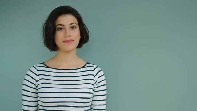 Portrait of young beautiful woman looking at the camera and smiling on blue background.