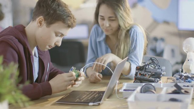 Girl and Boy Program Electronic Device with Laptop For Their Science/ Robotic/ Engineering Class at School. Shot on RED EPIC-W 8K Helium Cinema Camera.