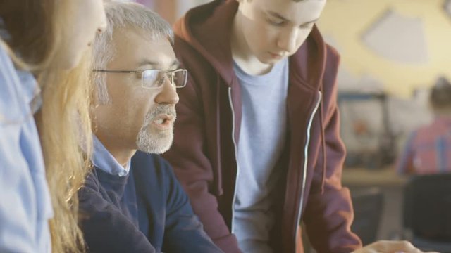 In Computer Science Class Teacher Examines Sketches of a programed Robot Engineered by Girl and Boy. Shot on RED EPIC-W 8K Helium Cinema Camera.