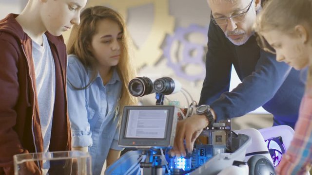 Teacher and His Pupils Work on a Programable Robot with LED Illumination for School Science Class Project. Shot on RED EPIC-W 8K Helium Cinema Camera.
