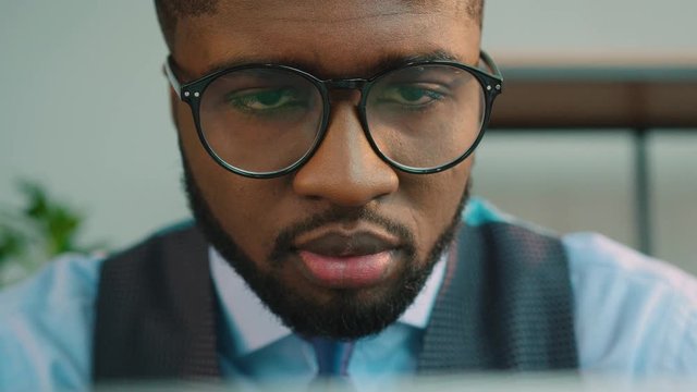 African American business man using laptop computer at the office. Black office worker typing on laptop keyboard and looking at the screen monitor. Close up